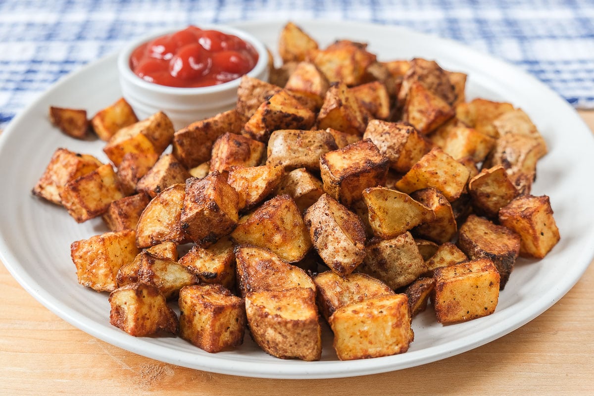 white plate of potatoes with ketchup for dipping