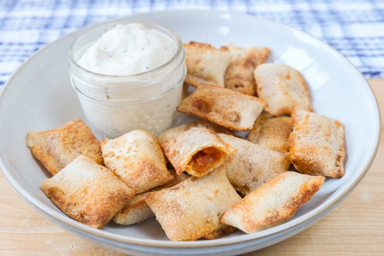 cooked pizza bites in bowl with dipping sauce behind