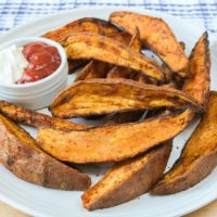 sweet potato wedges on white plate with dipping sauce in dish beside