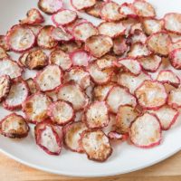 radish chips on white plate on wooden cutting board