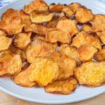 sweet potato chips on white plate with wood underneath