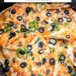 nachos with toppings including olives and cheese in air fryer with text overlay "nachos in the air fryer".