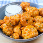orange buffalo cauliflower bites in blue bowl with dipping sauce