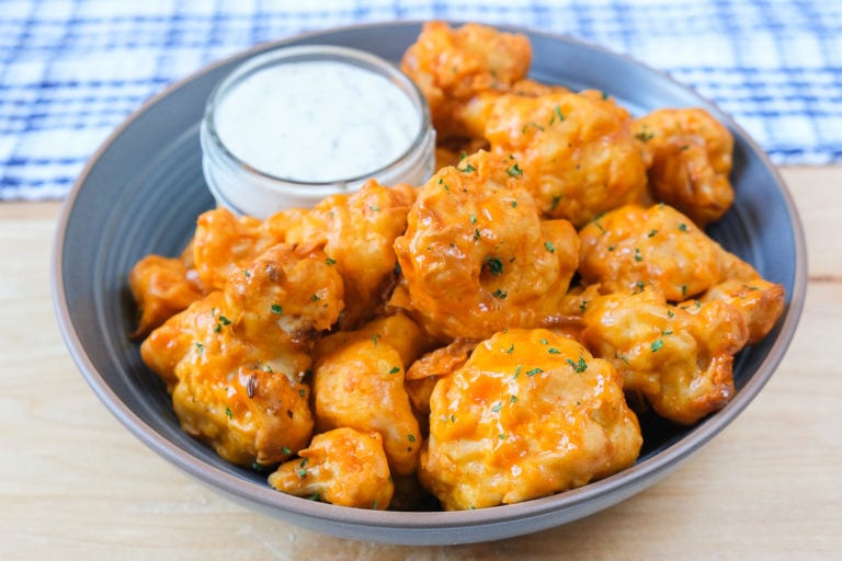 orange buffalo cauliflower bites in blue bowl with dipping sauce
