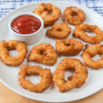 crispy calamari rings on white plate with ketchup dipping bowl beside