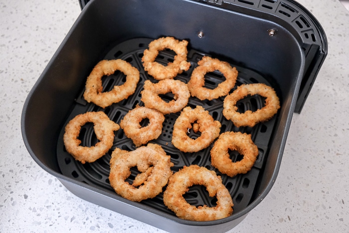 frozen calamari rings in black air fryer tray on white counter