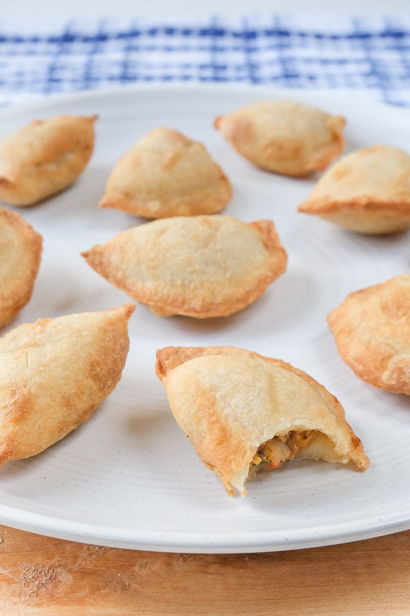 mini empanadas with bite out of it on white plate