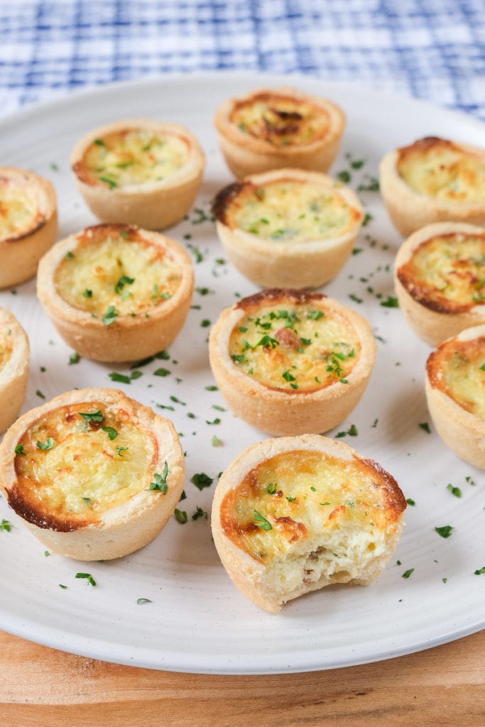 cooked mini quiche with bite out of it on white plate