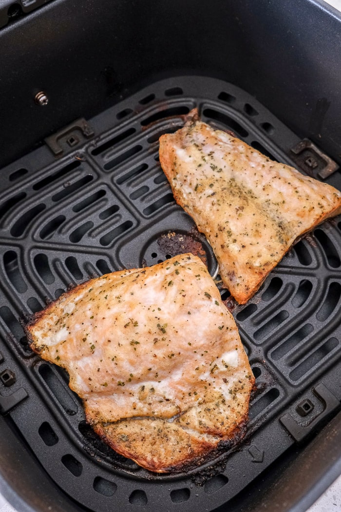 cooked salmon fillets in black air fryer tray on counter top