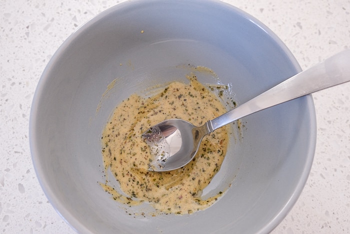 mixture of mustard and spices in blue bowl with spoon on white counter