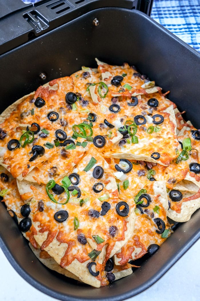 melted cheesy nachos in black air fryer tray on counter top