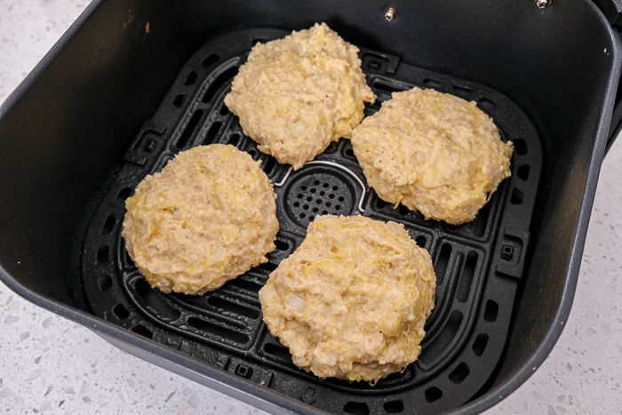 spaghetti squash fritters sitting in black air fryer tray on counter
