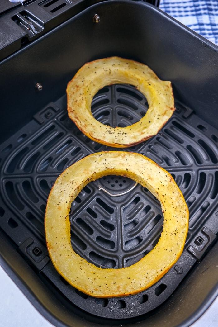 cooked spaghetti squash rings in black air fryer tray on counter