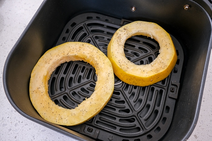 spaghetti squash rings in black air fryer tray on white counter