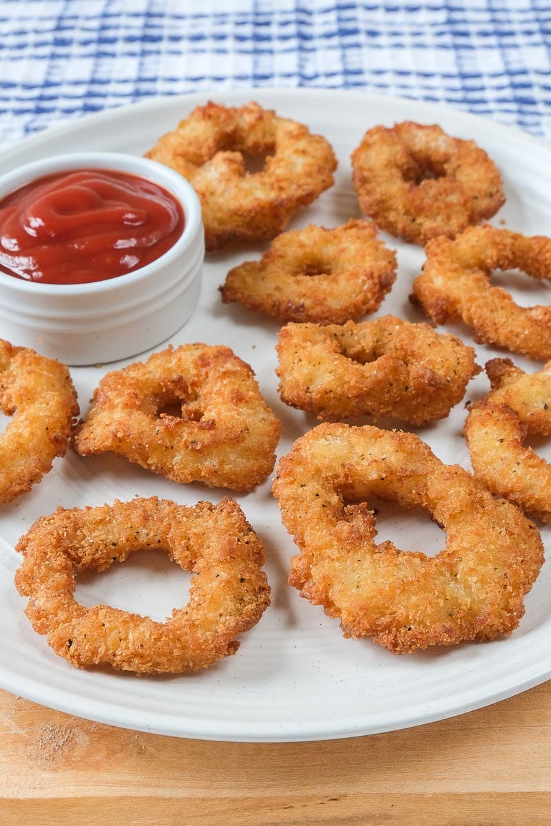 crispy calamari rings on white plate with red dipping sauce beside