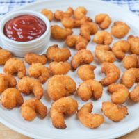 popcorn shrimp on plate with ketchup for dipping behind