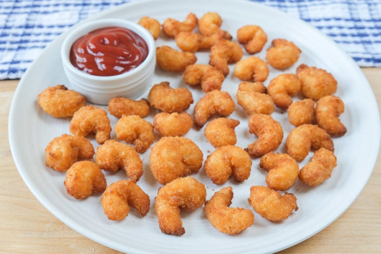 popcorn shrimp on plate with ketchup for dipping behind