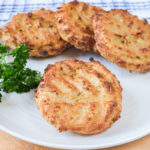 spaghetti squash fritters on white plate with green parsley beside