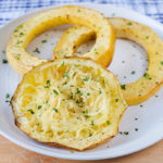 cooked spaghetti squash rings on white plate on wooden board