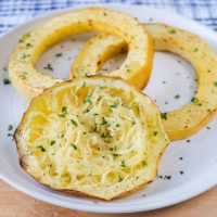 cooked spaghetti squash rings on white plate on wooden board