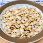 roasted spaghetti squash seeds on brown plate on wooden board