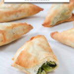 cooked spanakopita triangles on white plate with text overlay "frozen spanakopita in the air fryer".