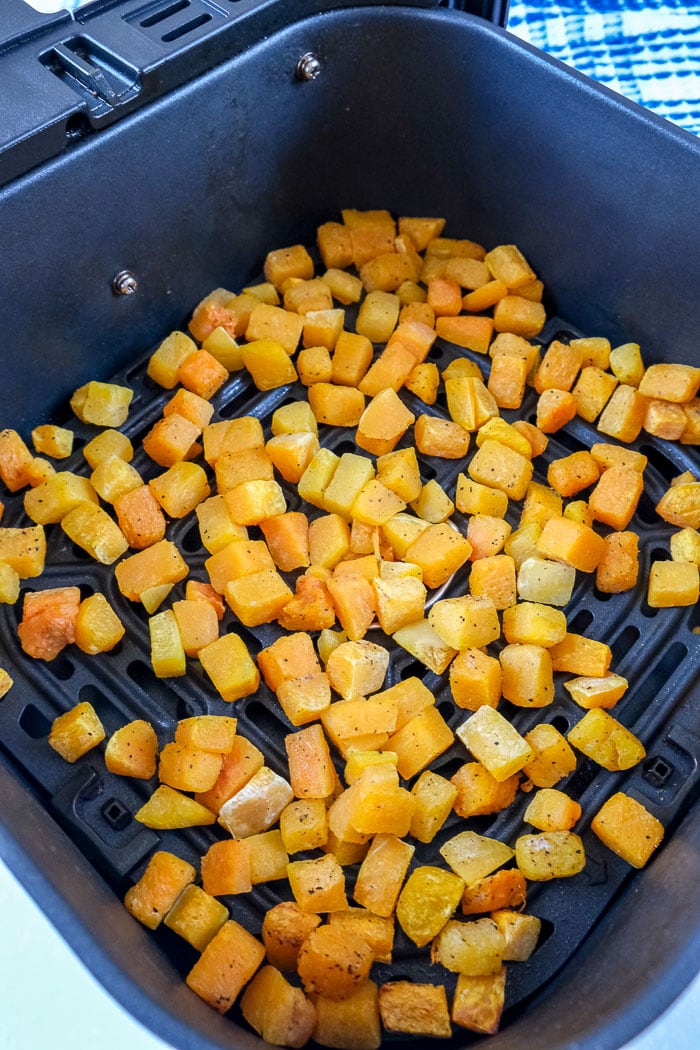 cooked butternut squash pieces in black air fryer tray on counter top