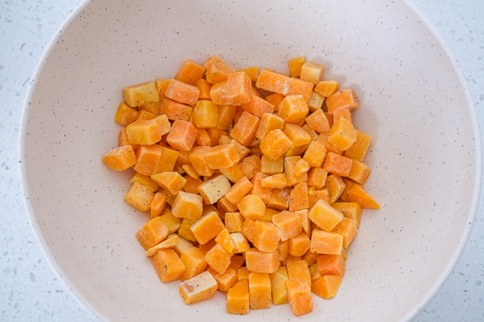 pieces of butternut squash in white bowl on white counter top