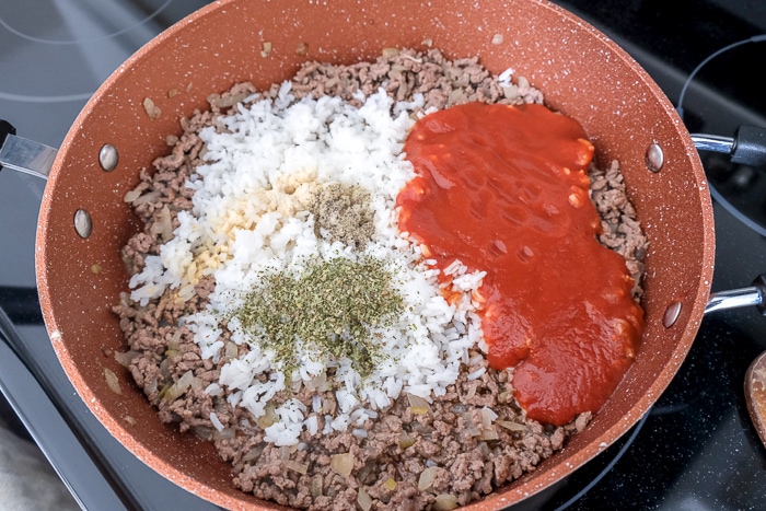 tomato sauce rice and spices in pan with minced beef on stove top