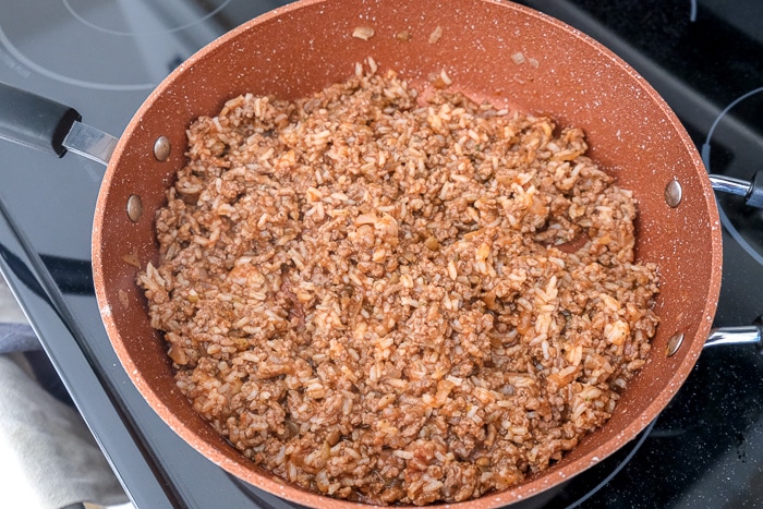 minced beef blended with rice in red pan on stove top