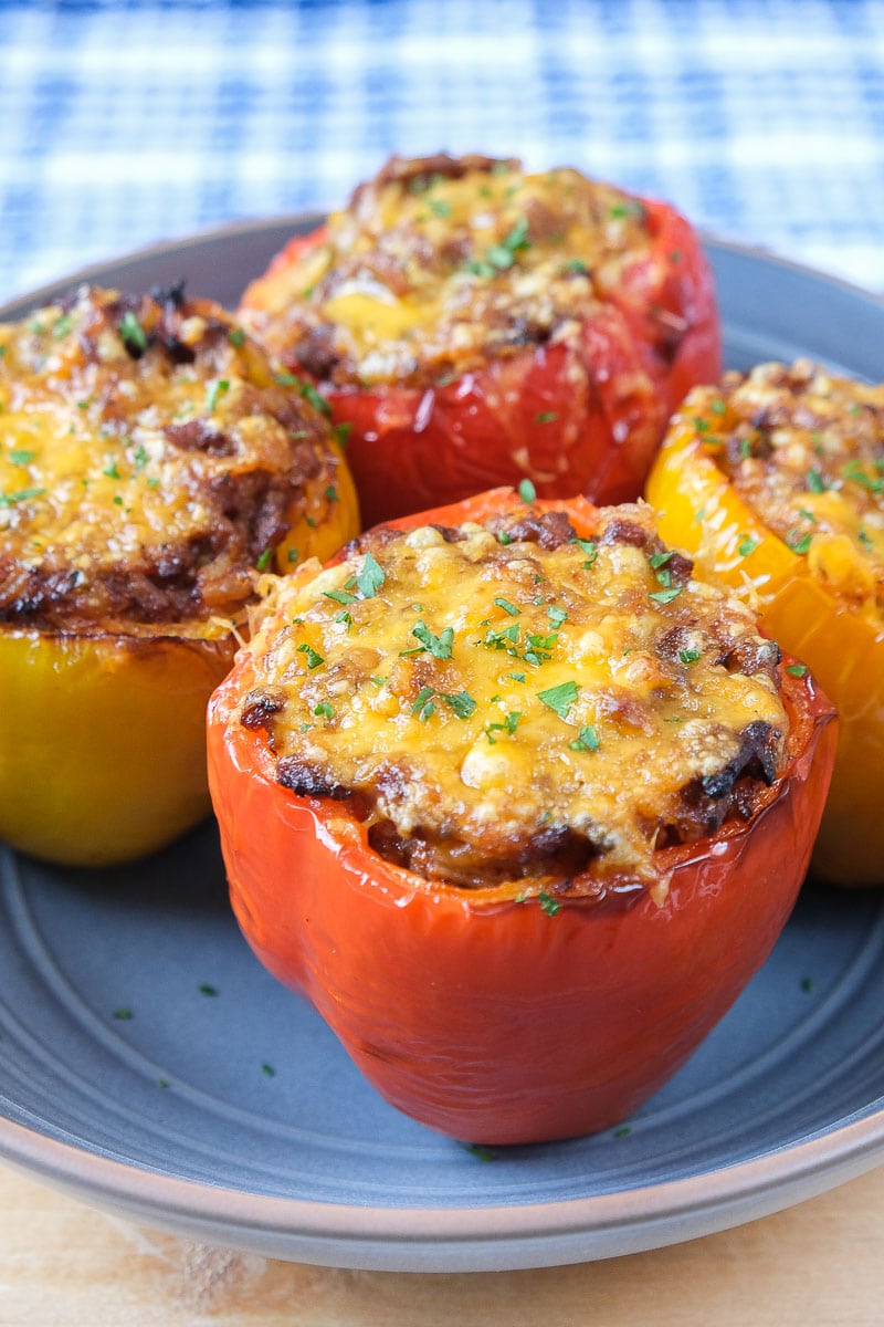 colorful stuffed peppers in blue bowl with melted cheese on top