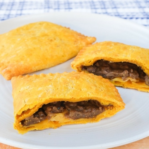 yellow jamaican beef patties on white plate cut in half