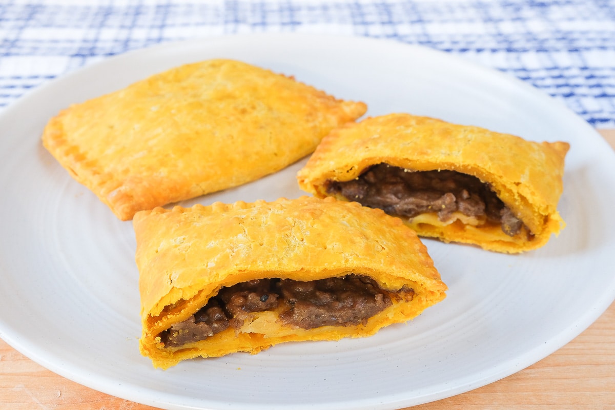 yellow jamaican beef patties on white plate cut in half