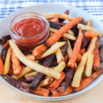 colorful veggie fries in bowl with ketchup on wooden board