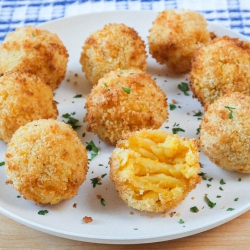 breaded mac and cheese balls on white plate with chopped parsley