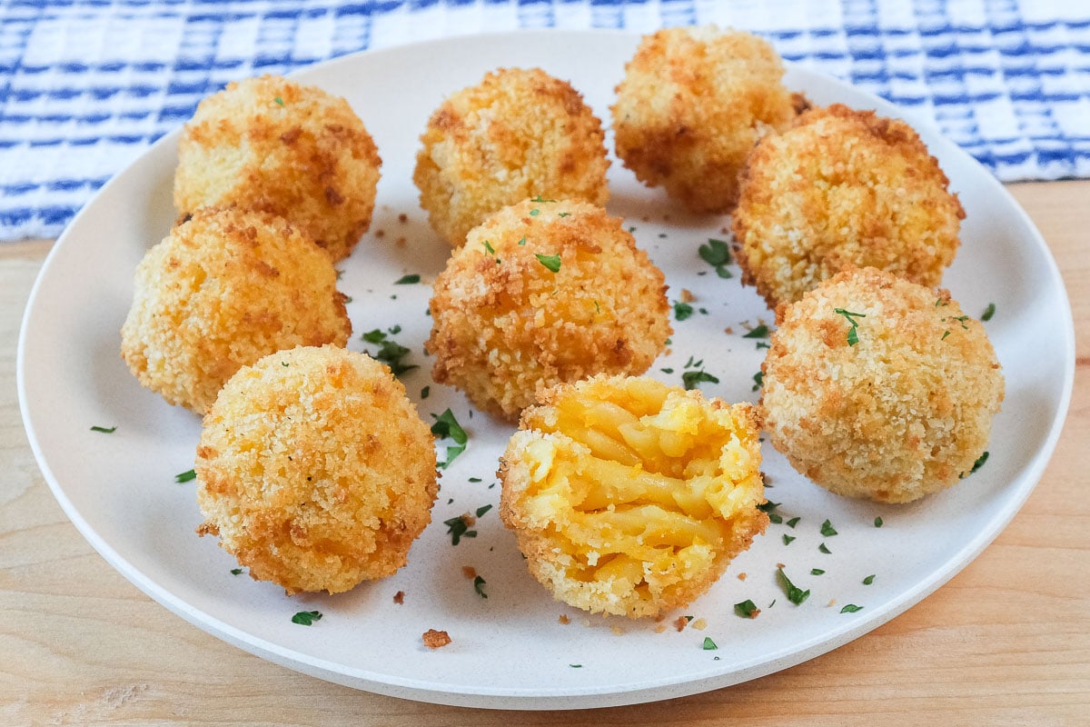 breaded mac and cheese balls on white plate with chopped parsley