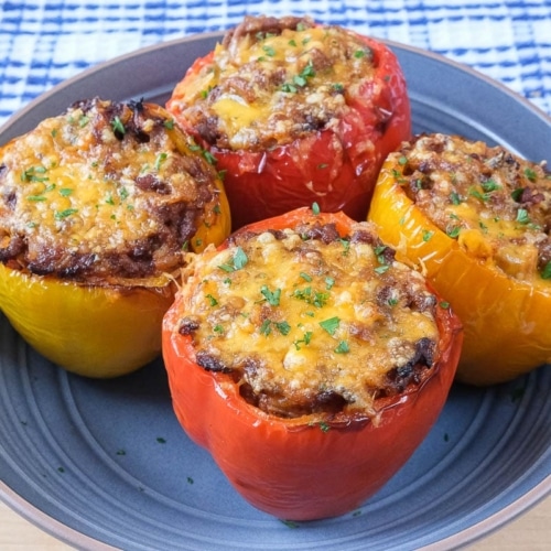 four colorful stuffed peppers in blue bowl on wooden board