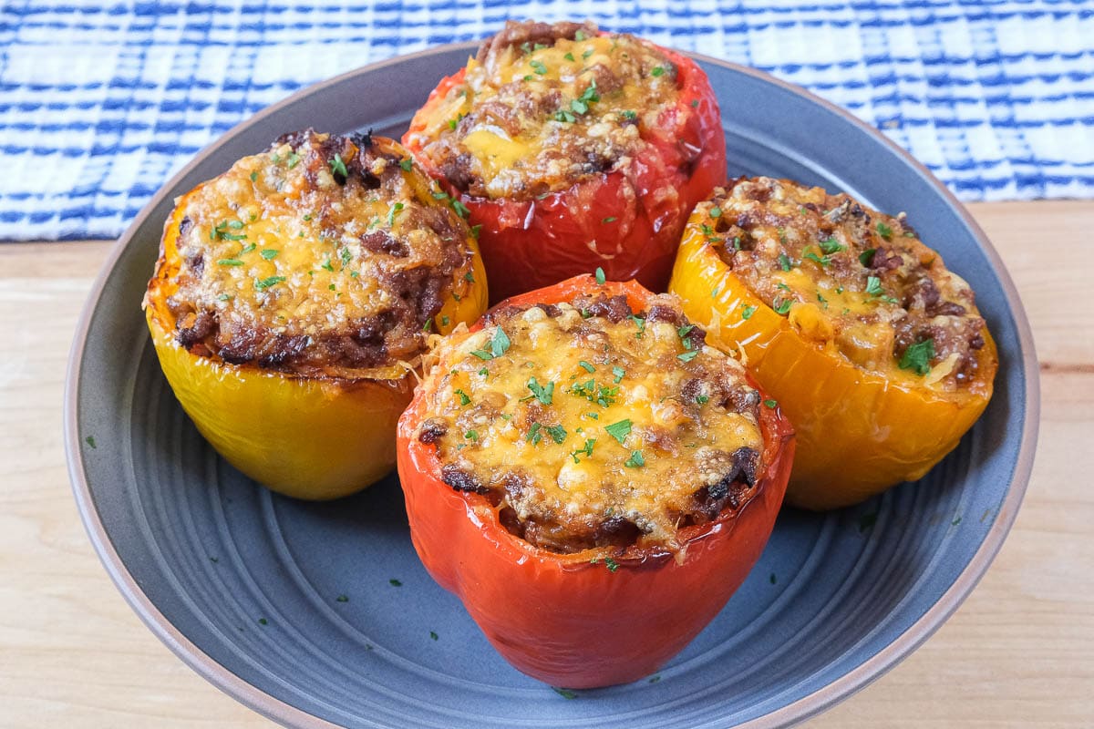 four colorful stuffed peppers in blue bowl on wooden board