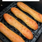 cooked breadsticks in black air fryer with text overlay "frozen breadsticks in the air fryer".