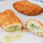 breaded chicken kiev cut in half on white plate