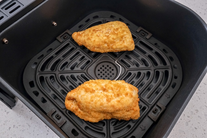 uncooked breaded chicken kiev in black air fryer tray on counter