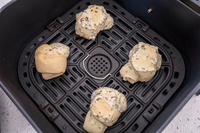 frozen garlic knots in black air fryer tray on white counter