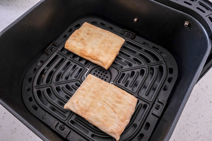 frozen toaster strudels in black air fryer tray on counter