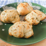 baked garlic knots on green plate on wooden board