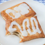 toaster strudel covered in icing on white plate on wooden board