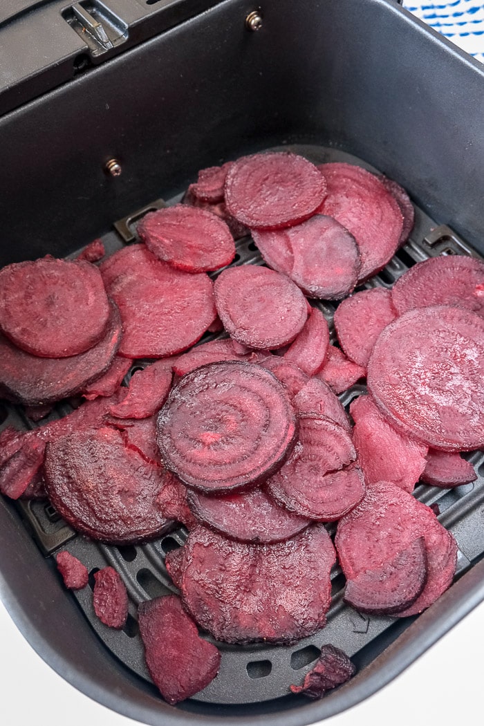 cooked sliced beets in black air fryer tray on white counter top.