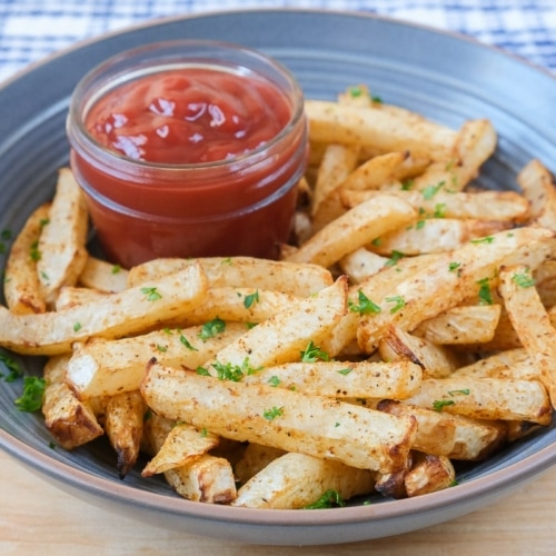 crispy turnip fries in blue bowl on wooden board with ketchup beside