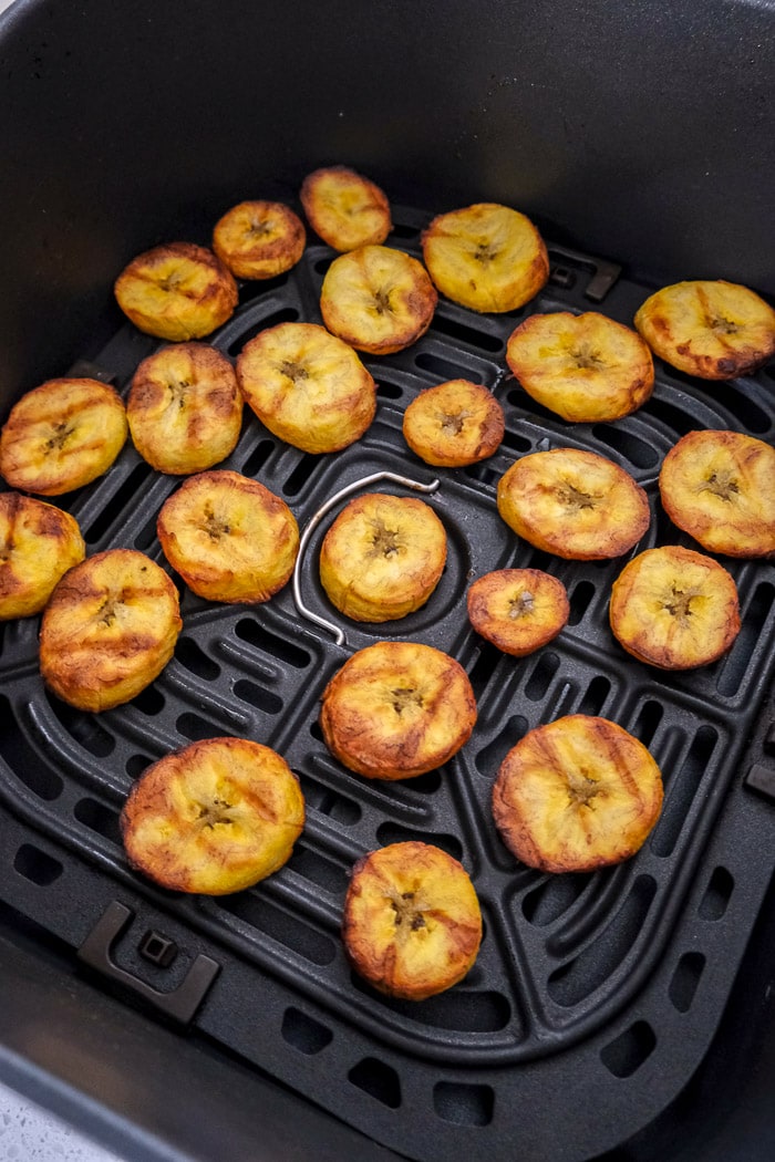 crispy plantain chips in black air fryer tray on counter.