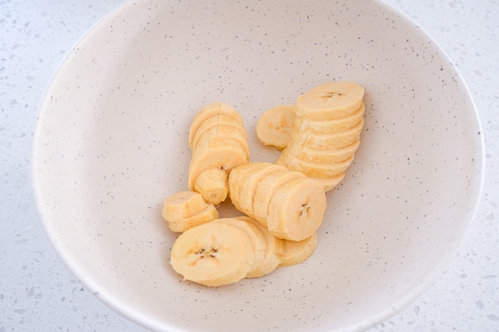 sliced plantains in white bowl on white counter.