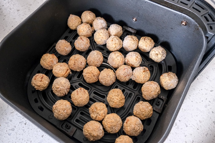 frozen turkey meatballs in black air fryer tray on counter top.